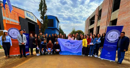 Group of people holding MEGA USA banner outside warehouse, promotional factory visit photo